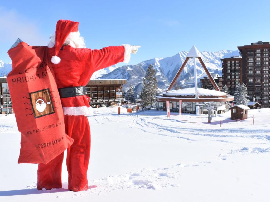 a man dressed as a santa claus standing in the snow at Studio Pegase Phenix-44 by Interhome in Le Corbier