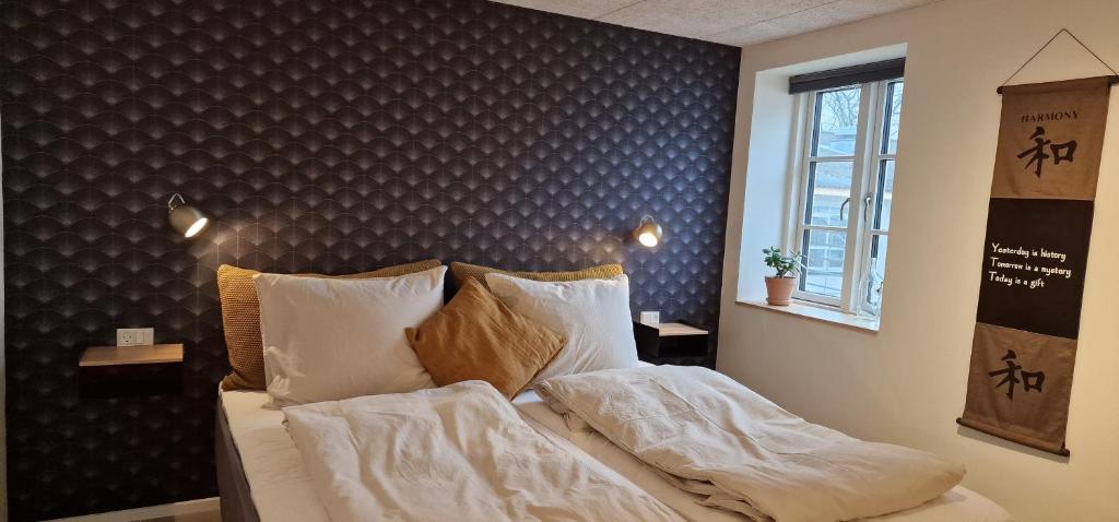 a bedroom with a bed with white sheets and pillows at Molsgaarden in Knebel