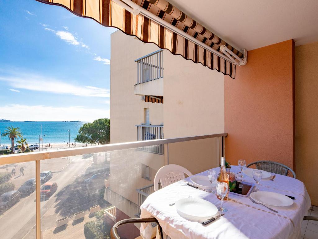 une salle à manger avec une table et un balcon donnant sur l'océan. dans l'établissement Apartment Le Capitole-3 by Interhome, à Fréjus