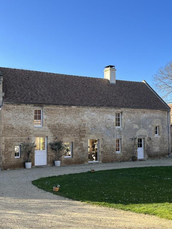 a large stone building with a driveway in front of it at Les Granges Pelloquin in Bernières-sur-Mer