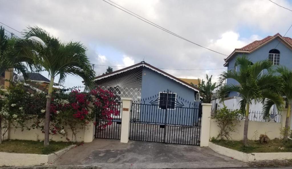 a blue house with a gate and palm trees at Oak Villa Montego Bay in Montego Bay