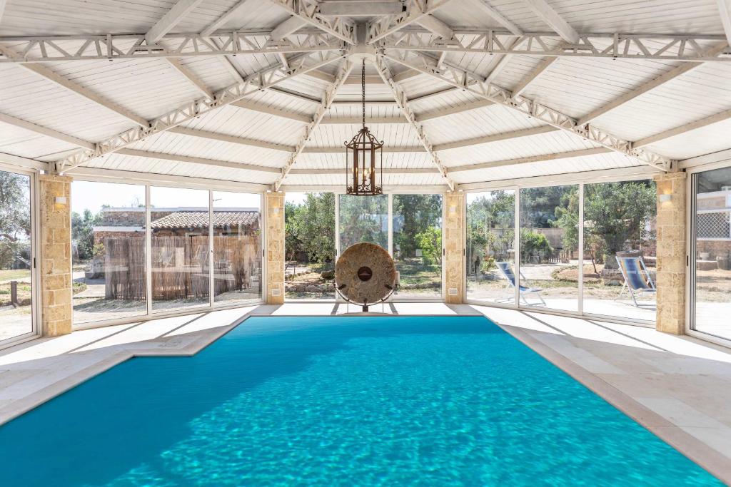een binnenzwembad met een wit plafond en ramen bij Villa Antonietta in Alliste