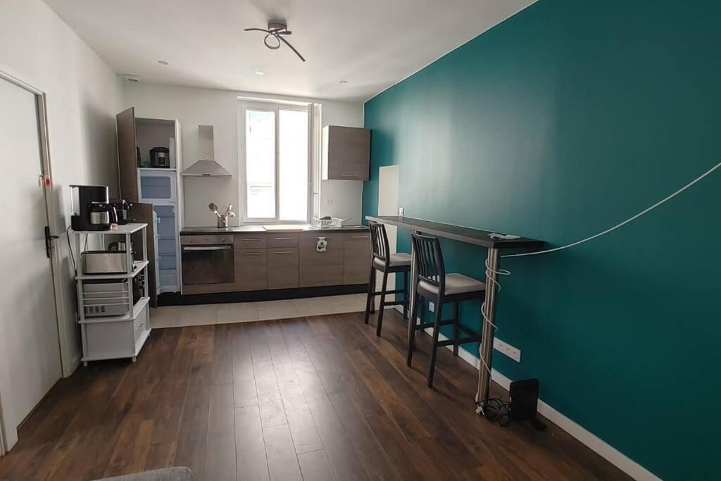 a kitchen with a blue wall and a table and chairs at Appartement 5 chambres tous conforts - WIFI - TV in Saint-Étienne