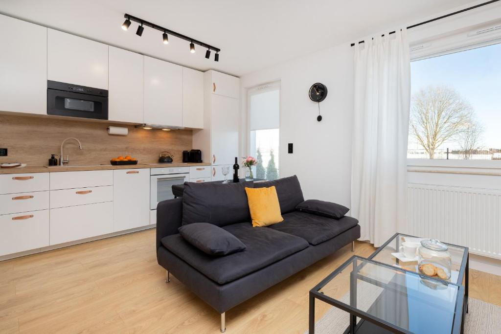 uma sala de estar com um sofá preto e uma cozinha em Butterfly Apartment with Parking by Renters em Gdańsk