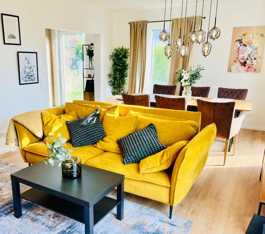 a yellow couch in a living room with a table at Wasserspaß pur - Luxus Ferienhaus bei Berlin, direkt am Wasser, inkl SUPs und Schlauchboot! in Oranienburg
