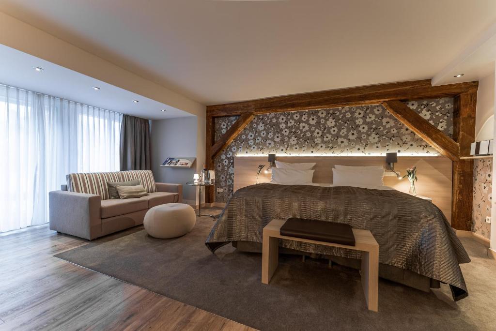 - une chambre avec un lit, un canapé et une chaise dans l'établissement Hotel An der Wasserburg, à Wolfsburg