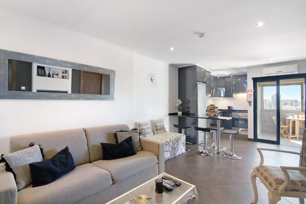 Una sala de estar con un sofá y una cocina. en Apartamento Freire, en Portimão