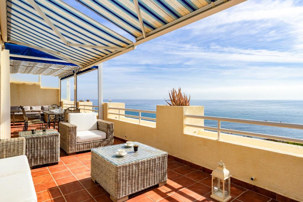 einen Balkon mit Stühlen und Tischen sowie Meerblick in der Unterkunft Seaview terrace by the beach in El Faro Ref 93 in Mijas Costa