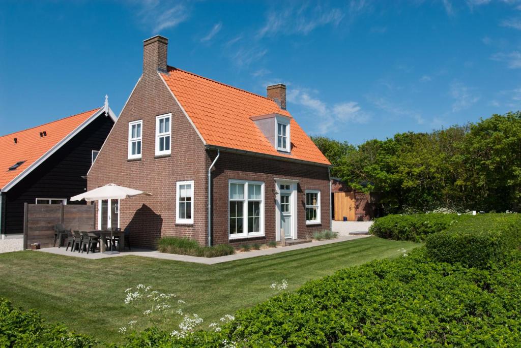 een stenen huis met een oranje dak bij Vakantieverblijf de Trommel in Domburg