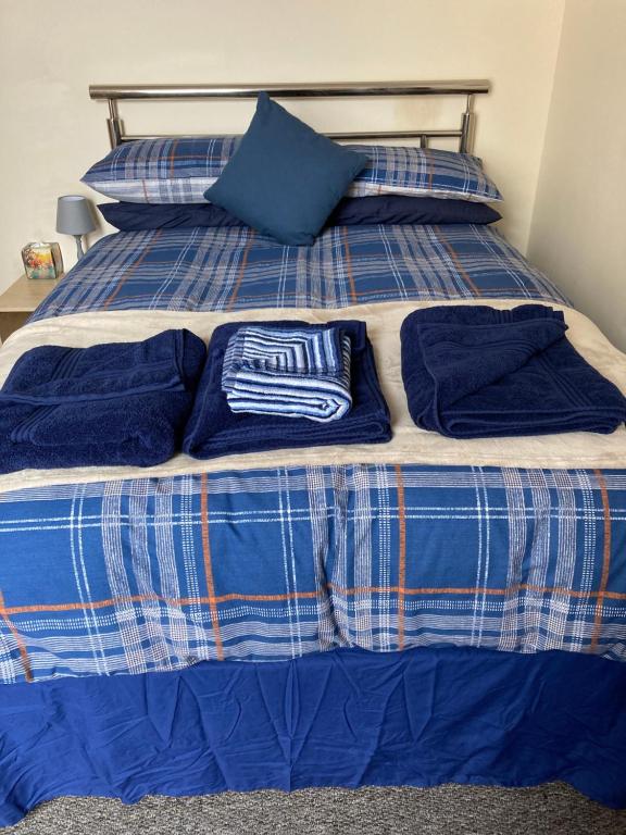 a bed with blue and white sheets and blue pillows at Happy Holiday apartments in Mablethorpe