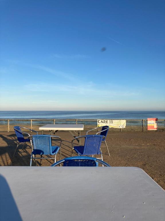 a table and chairs on a beach with the ocean at Happy Holiday apartments in Mablethorpe