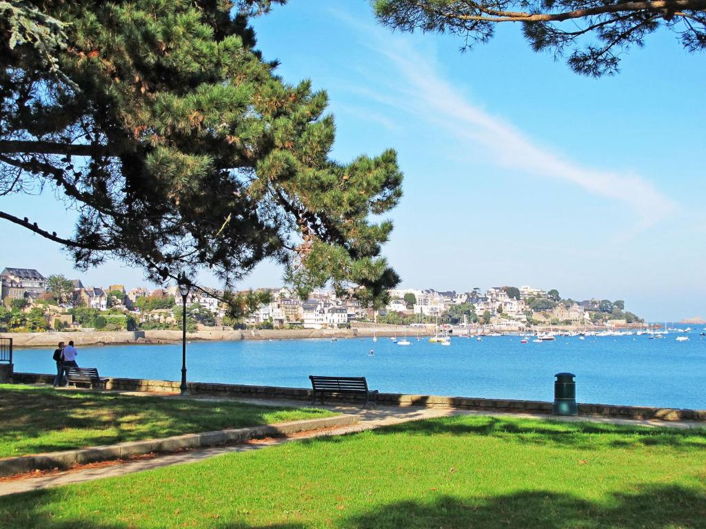 a person sitting on a park bench near the water at Studio La Garde by Interhome in Dinard