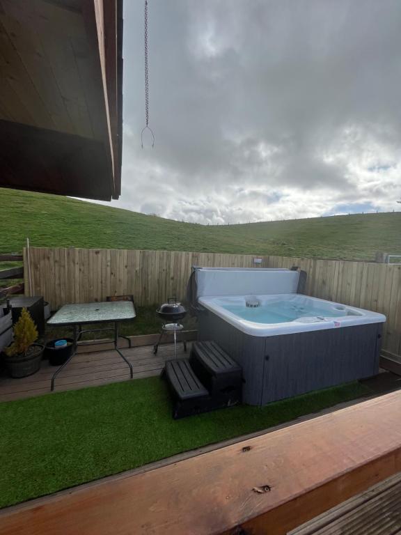 a hot tub in a yard with a table and a bench at East Learmouth Lakeside Lodges in Cornhill-on-tweed
