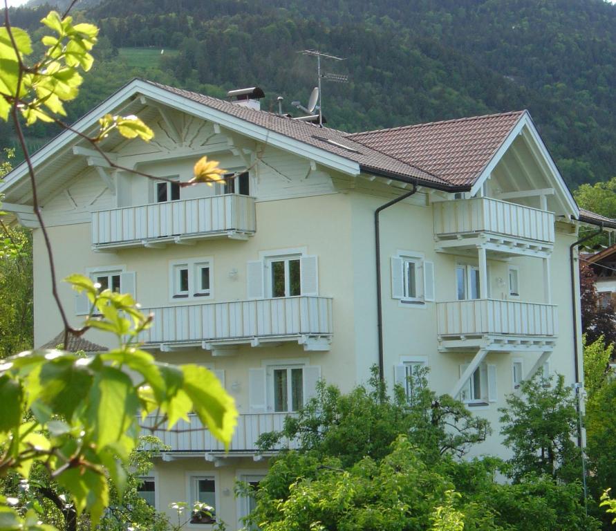 a white building with white balconies and trees at Residence Adler in Tesimo