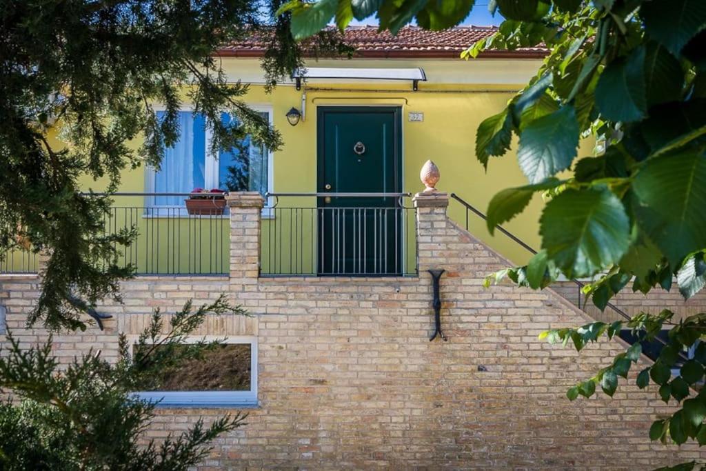 a yellow house with a green door on a brick staircase at Casa in campagna la Roverella in Francavilla dʼEte