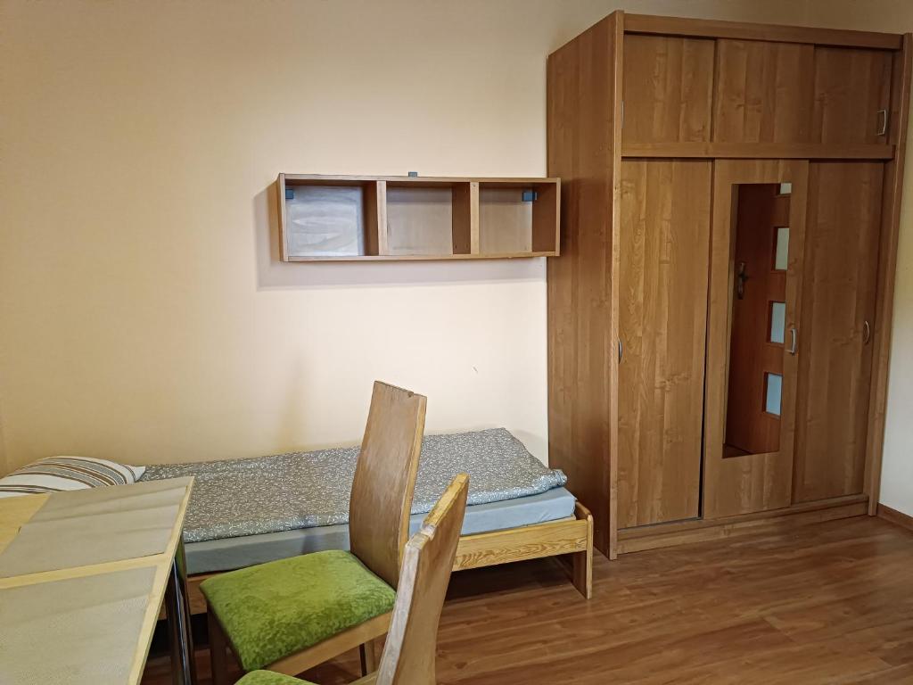 a room with a bed and a table and a cabinet at Hostel Sunrise Liwska in Warsaw