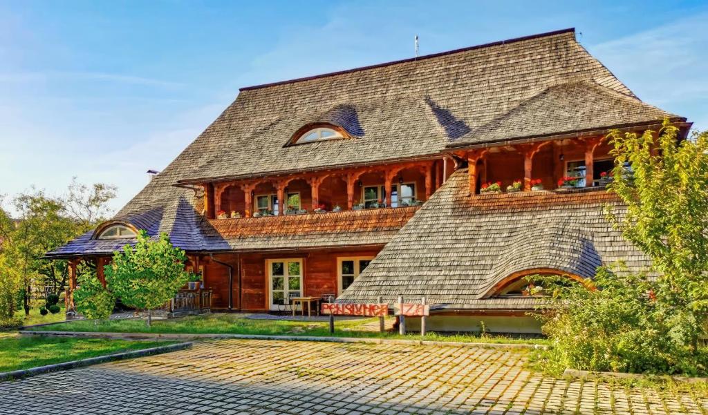 uma casa grande com um telhado de gambrel em Pensiunea Iza em Viseu de Jos