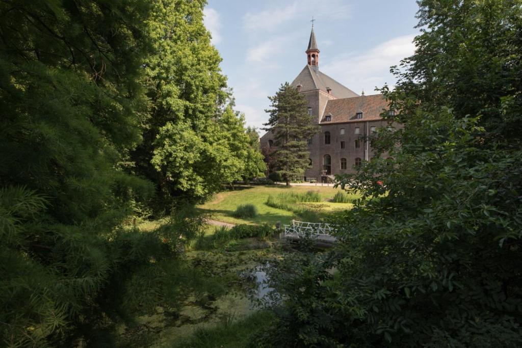 a building in the middle of a field with a river at Het Rustpunt in Ghent