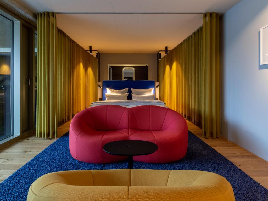 a bedroom with a red couch in front of a bed at b'mine hotel Düsseldorf in Düsseldorf