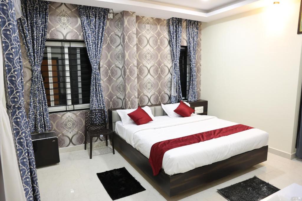 a bedroom with a large bed with red pillows at Sunshine International Boarding & Lodging in Belūr