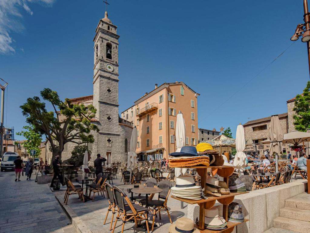a street with a clock tower and tables and chairs at Apartment Stanatura-4 by Interhome in Porto-Vecchio