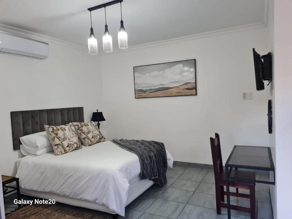 a white bedroom with a bed and a table at Egerton Overnight in Kimberley