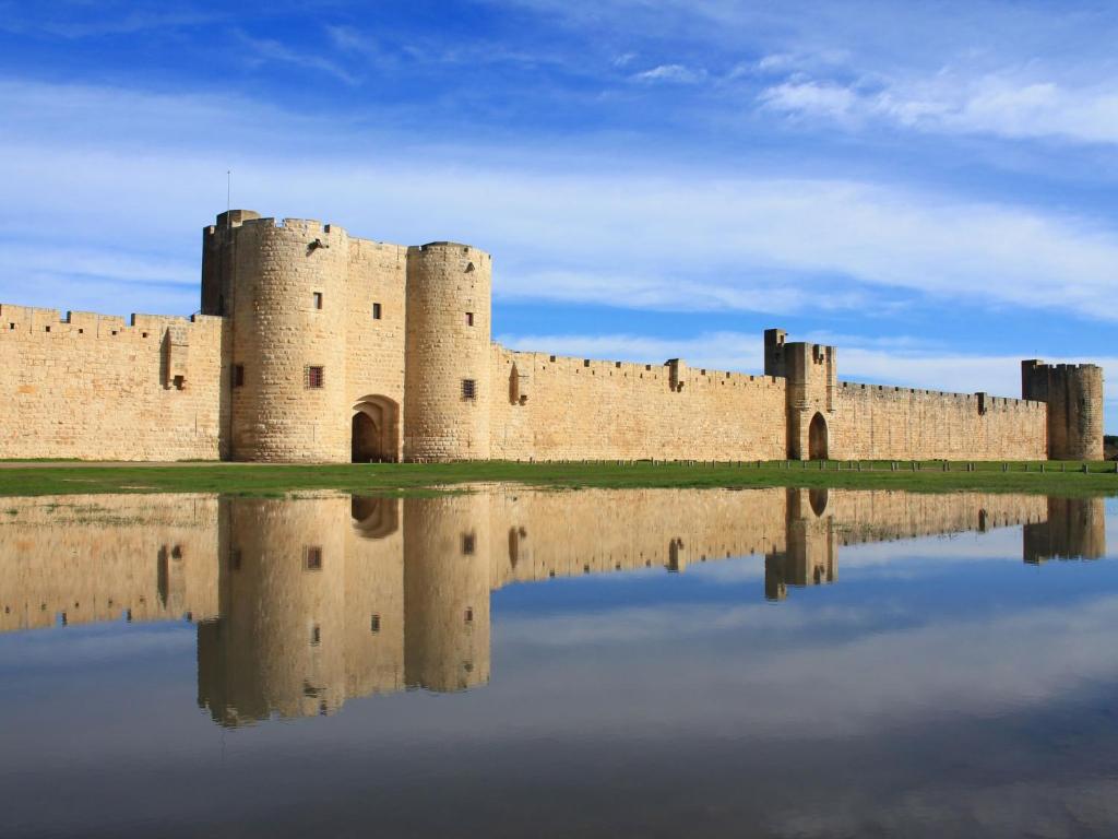 a castle with its reflection in a body of water at Holiday Home La Maison Theaulon by Interhome in Aigues-Mortes