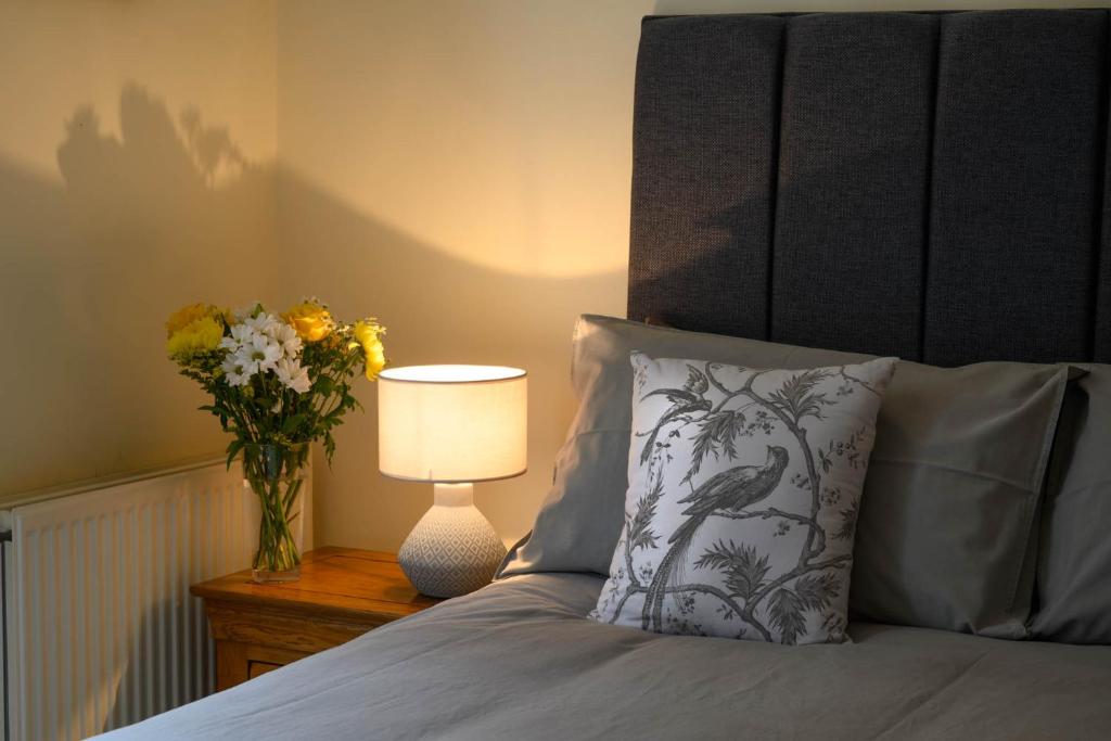 Un dormitorio con una cama con un jarrón de flores y una lámpara en The Farmhouse B&B en Dunkeld