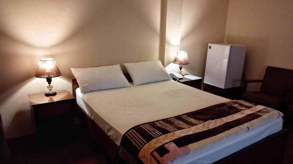 a bedroom with a bed with two lamps and a chair at Canal view hotel in Faisalabad