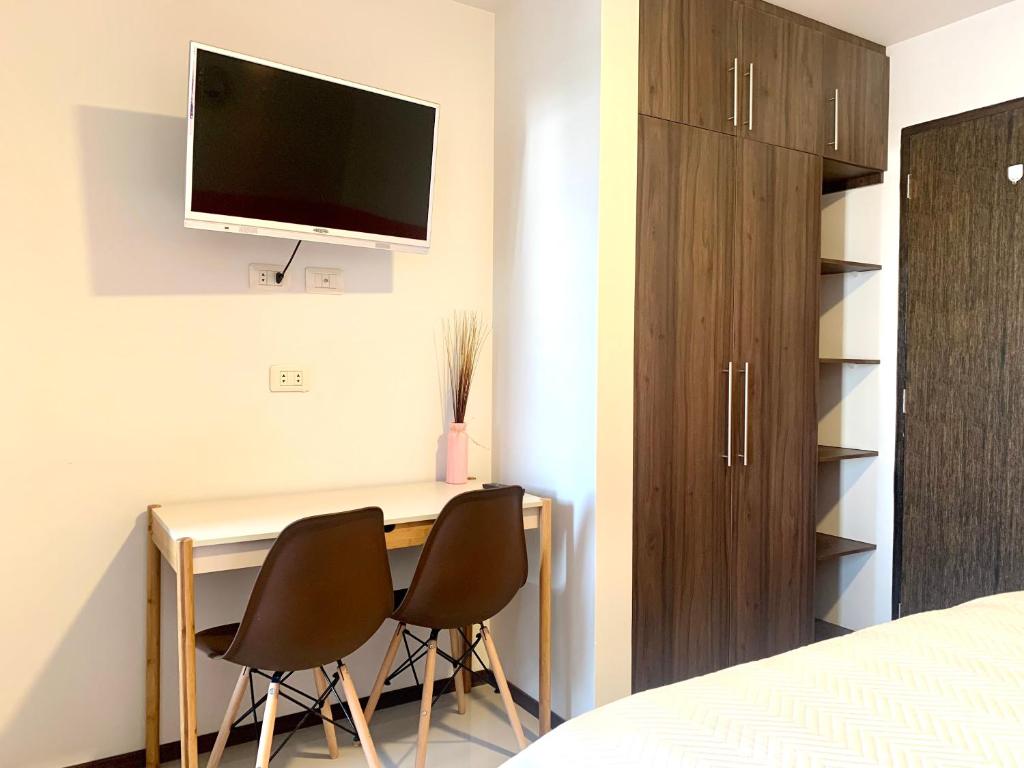 Cette chambre comprend un bureau avec 2 chaises et une télévision murale. dans l'établissement Studio Coral en la mejor Zona de Cochabamba, à Cochabamba
