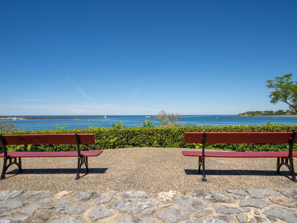 two red benches sitting next to the ocean at Studio La Pergola-8 by Interhome in Saint-Jean-de-Luz