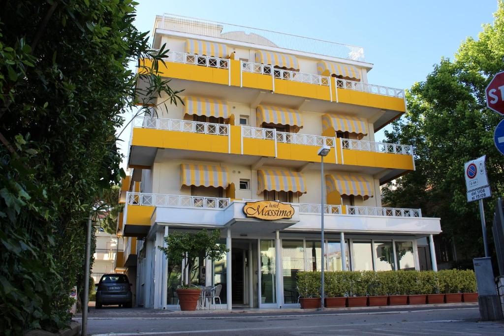 a yellow building with a sign in front of it at Hotel Massimo in Riccione