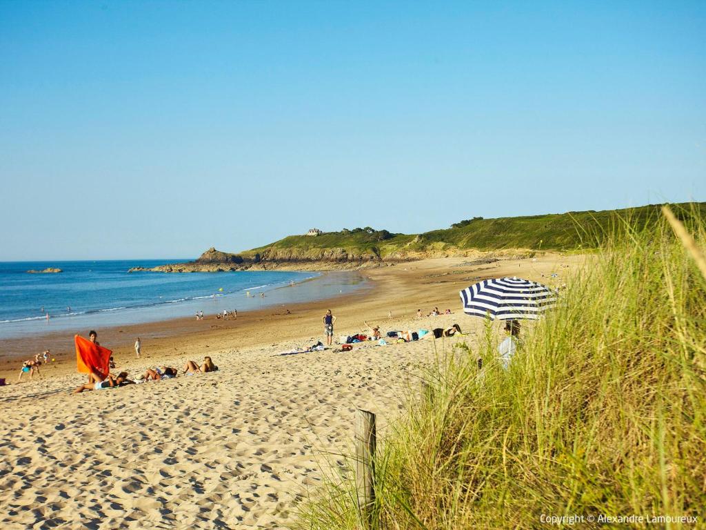 a beach with people laying on the sand and an umbrella at Holiday Home La Vallée by Interhome in Cancale