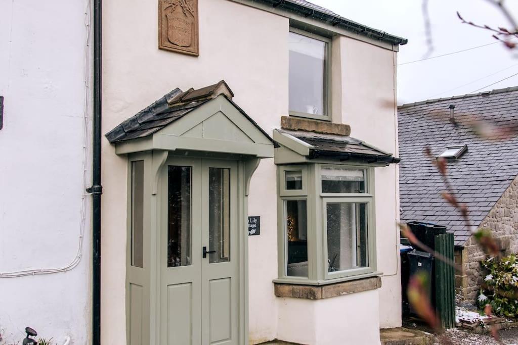 a white house with a green door and a window at Ava Lily Cottage, Tideswell in Tideswell