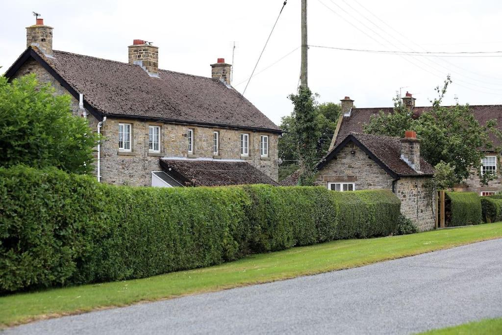 a house with a hedge in front of a street at Cliff Stud Retreat, Helmsley, Frankel Cottage in Helmsley