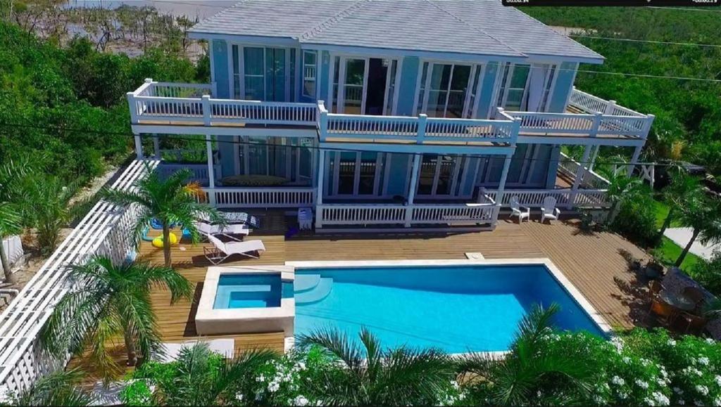 a blue house with a swimming pool in front of it at Sea Walk home in Governorʼs Harbour