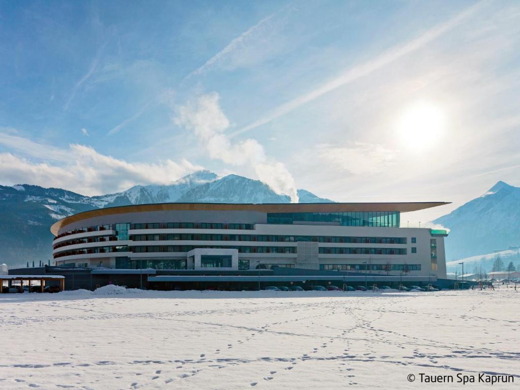 a large building with snow in front of mountains at Apartment Appartment Wiesberg by Interhome in Niedernsill