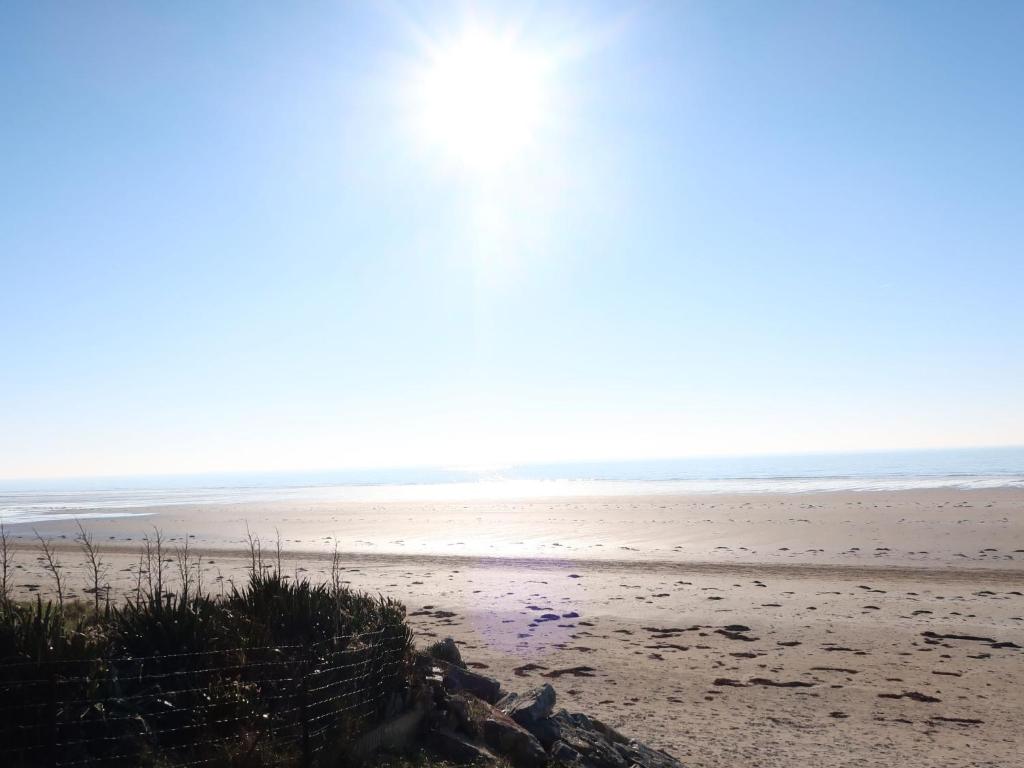 a beach with the sun shining on the sand at Holiday Home La Plage by Interhome in Denneville
