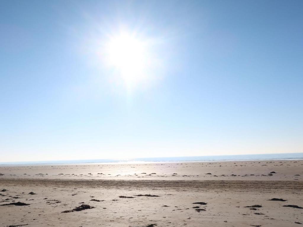 an empty beach with the sun in the sky at Holiday Home La Plage by Interhome in Denneville