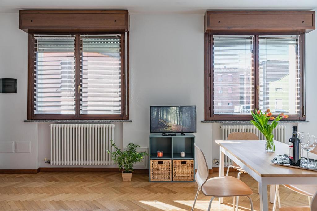 a living room with a table and two windows at Parma Parco Ducale Duplex Apartment with parking in Parma