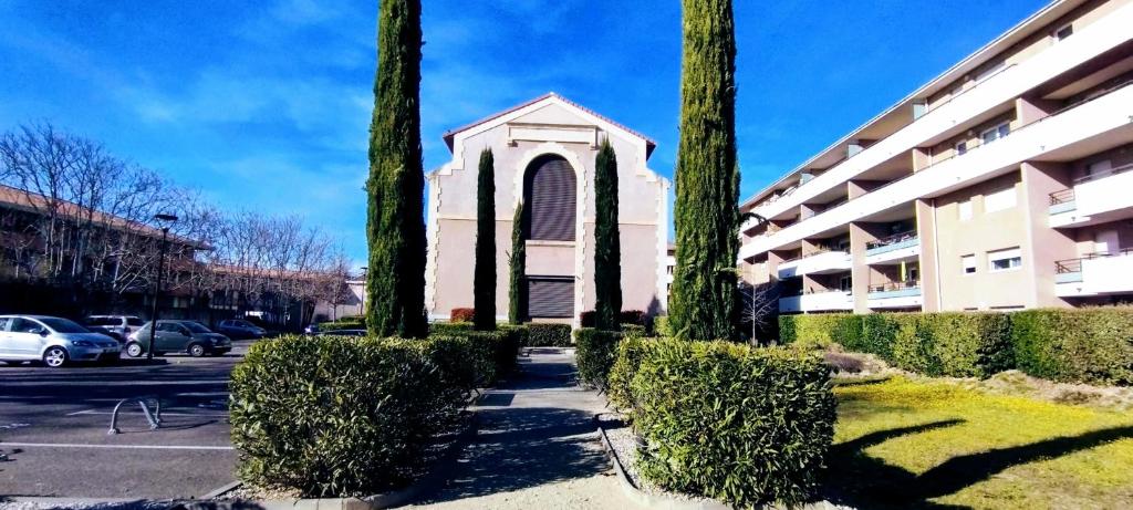 une église avec des arbres devant un bâtiment dans l'établissement Mambrillo Parking Netflix Disney Prime, à Avignon