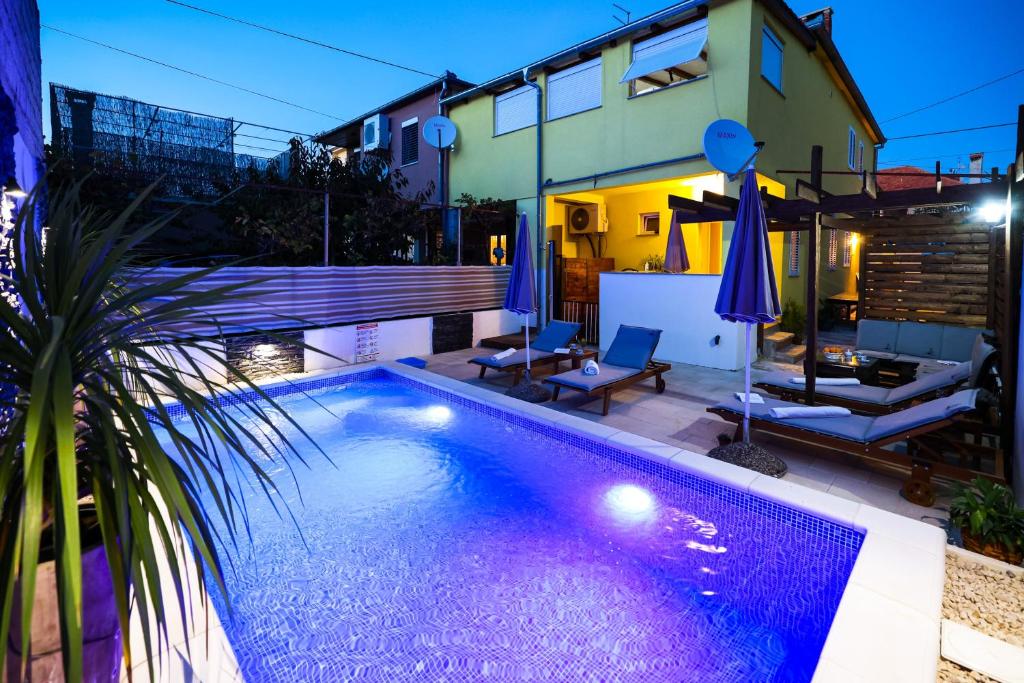 ein Schwimmbad vor einem Haus in der Nacht in der Unterkunft 2 bedrooms appartement with private pool enclosed garden and wifi at Zadar 2 km away from the beach in Zadar
