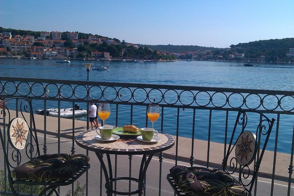 einen Tisch mit einem Teller mit Speisen und Getränken auf dem Balkon in der Unterkunft Apartment Milka with sea view and boat place in Tisno