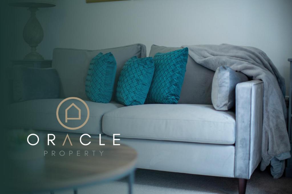 un sofá blanco con almohadas azules en la sala de estar. en Modern House with FREE Private Parking, WIFI & Netflix, en Stratford-upon-Avon
