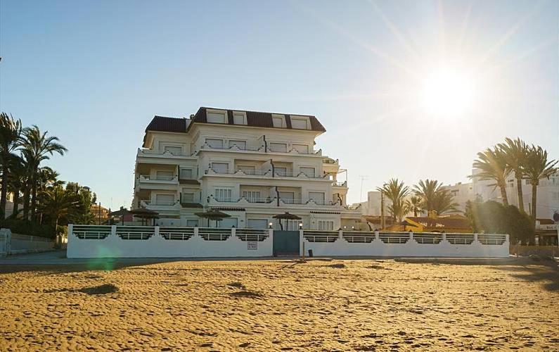 un gran edificio blanco en una playa con palmeras en Ático Medina Molins, en Denia