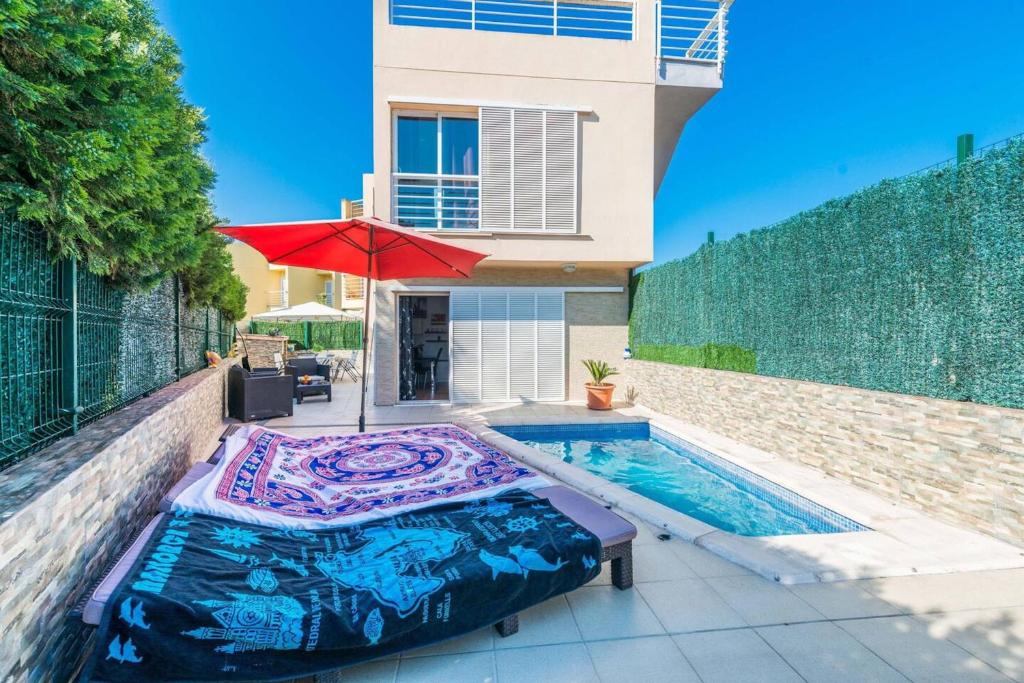 a swimming pool with a bed and an umbrella next to a house at Comfortable House in Puerto de Alcudia with Private Pool in Port d'Alcudia