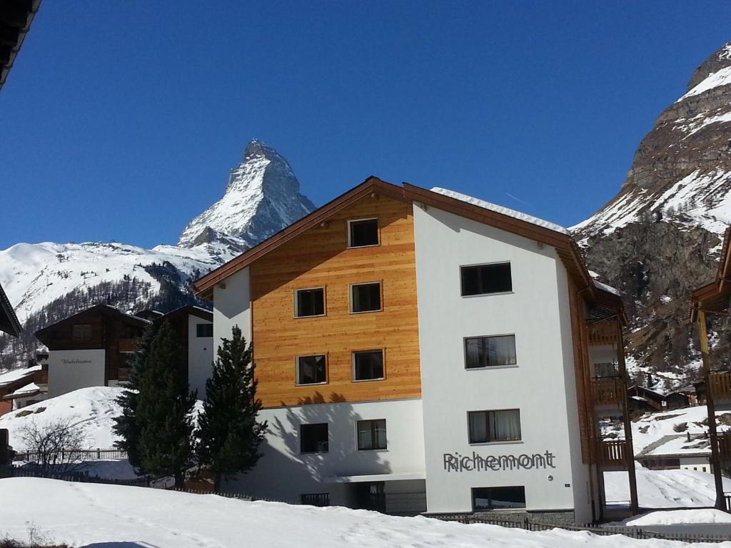 un edificio en la nieve con una montaña en el fondo en Haus Richemont, en Zermatt