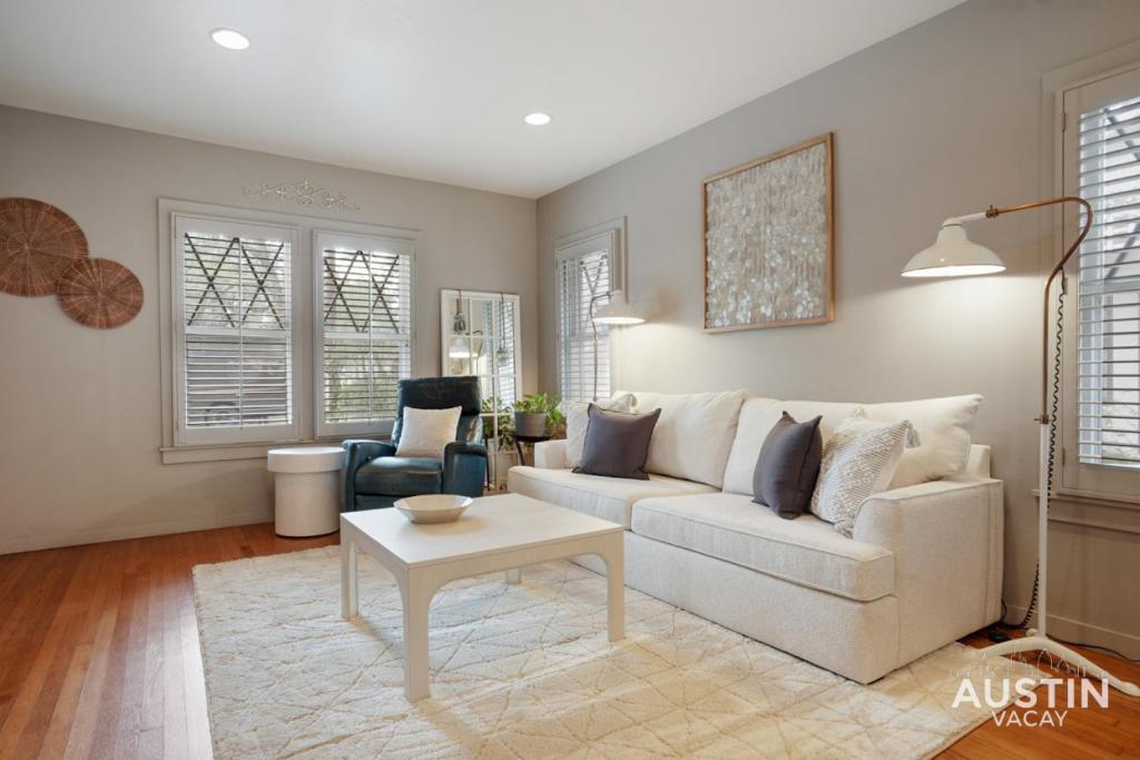 a living room with a white couch and a table at Entertaining Charmer w Outdoor Games and Putt-Putt in Austin