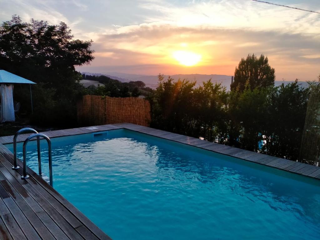 una piscina con puesta de sol en el fondo en One bedroom house with sea view shared pool and enclosed garden at Montelabbate, en Montelabbate