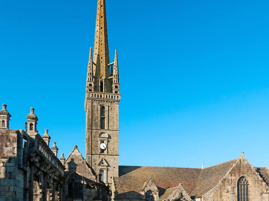 a church with a tall tower with a clock on it at Holiday Home Blaue Hortensie - SZN100 by Interhome in Sizun